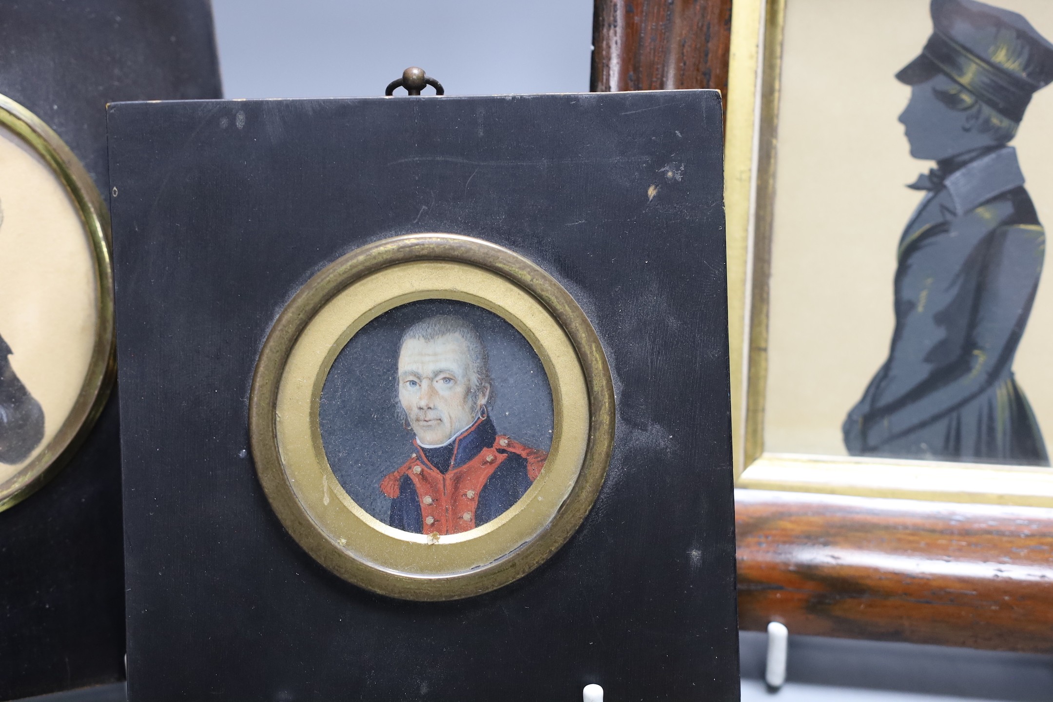 An unusual portrait miniature of a 19th century gentleman wearing earrings, together with two framed silhouettes (3)